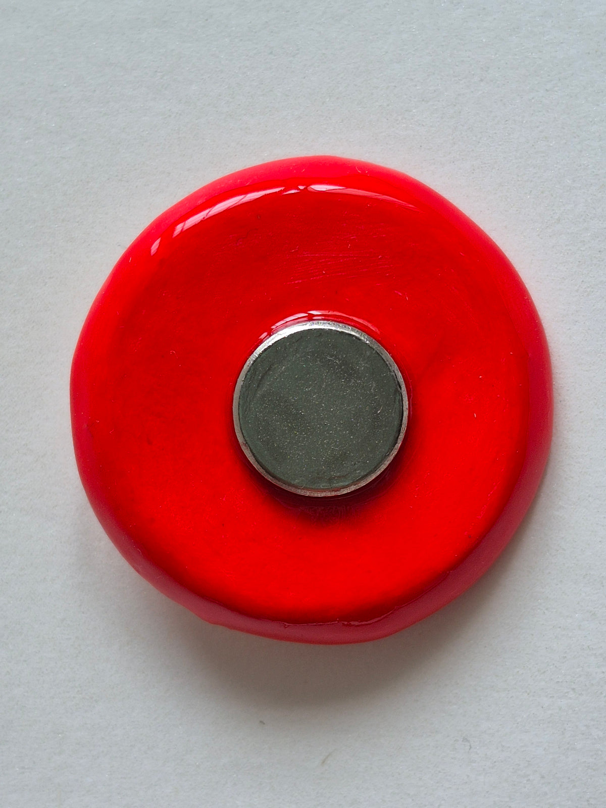 The flat back of a red circular plate with circular magnet. Back of the plate of soft-boiled eggs.